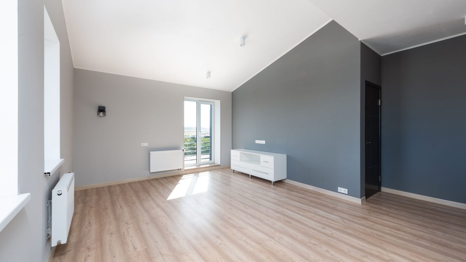 Pièce d'un logement neuf aux murs gris clair avec un mur d'accent gris foncé et un parquet clair