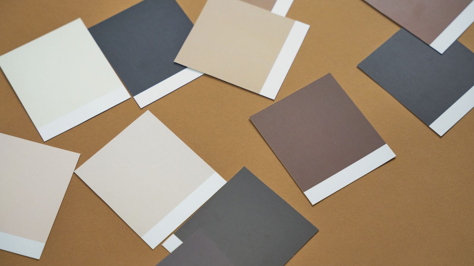 Échantillons de couleurs de peinture en teintes neutres, blancs, gris et marron, posés sur du papier kraft
