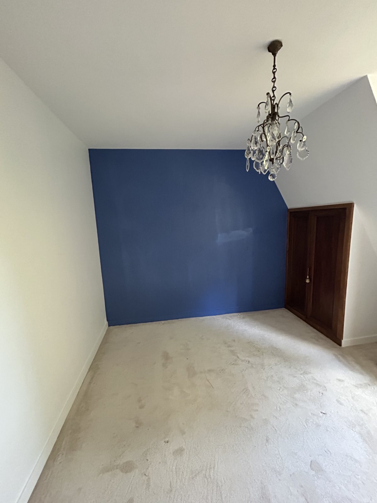 Chambre mansardée avec mur d'accent bleu roi, lustre à pampilles et armoire bois, peinture livrée avant la pose du sol - Yvelines