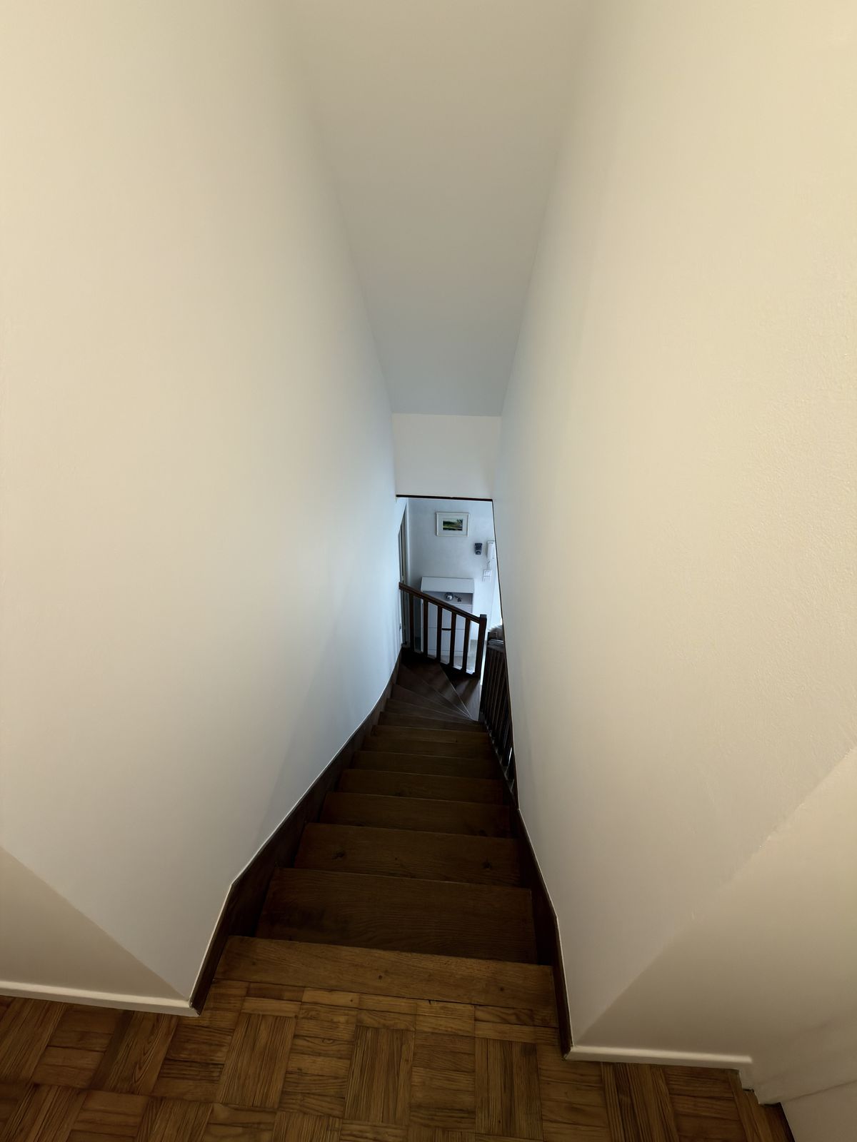 Montée d'escalier vue du palier après peinture, murs blancs et marches bois - Yvelines