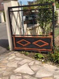 Peinture extérieure : portail métallique rénové, motifs orange sur noir