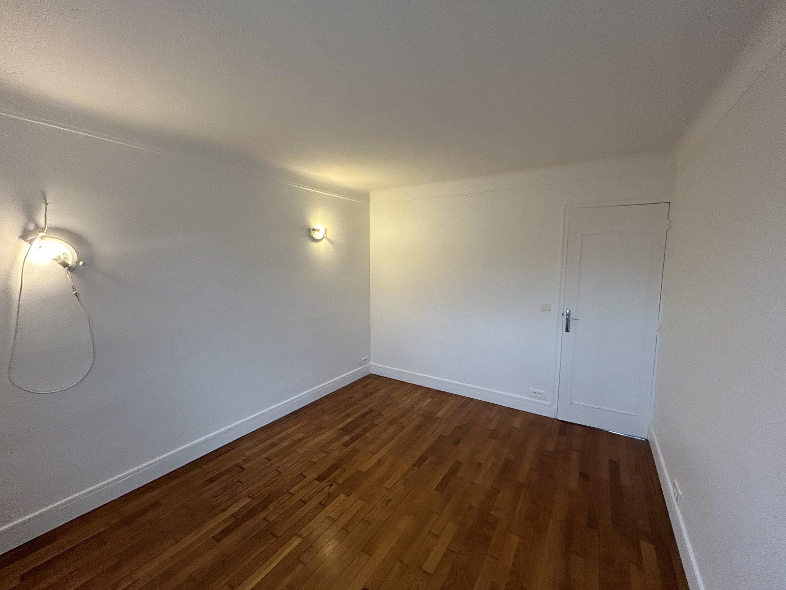 Chambre repeinte en blanc mat, appliques murales, porte blanche et parquet bois foncé - Yvelines